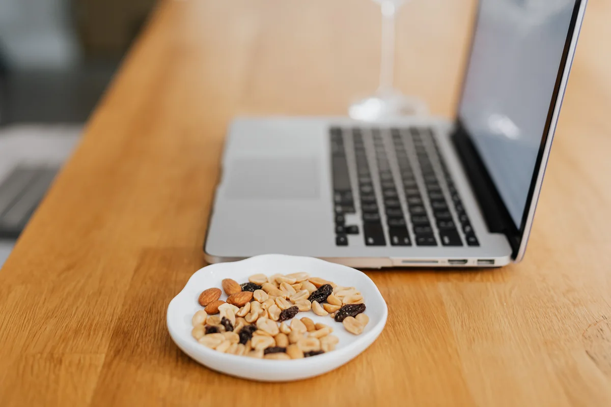 Meal-planning research workspace with a laptop and a bowl of nuts.