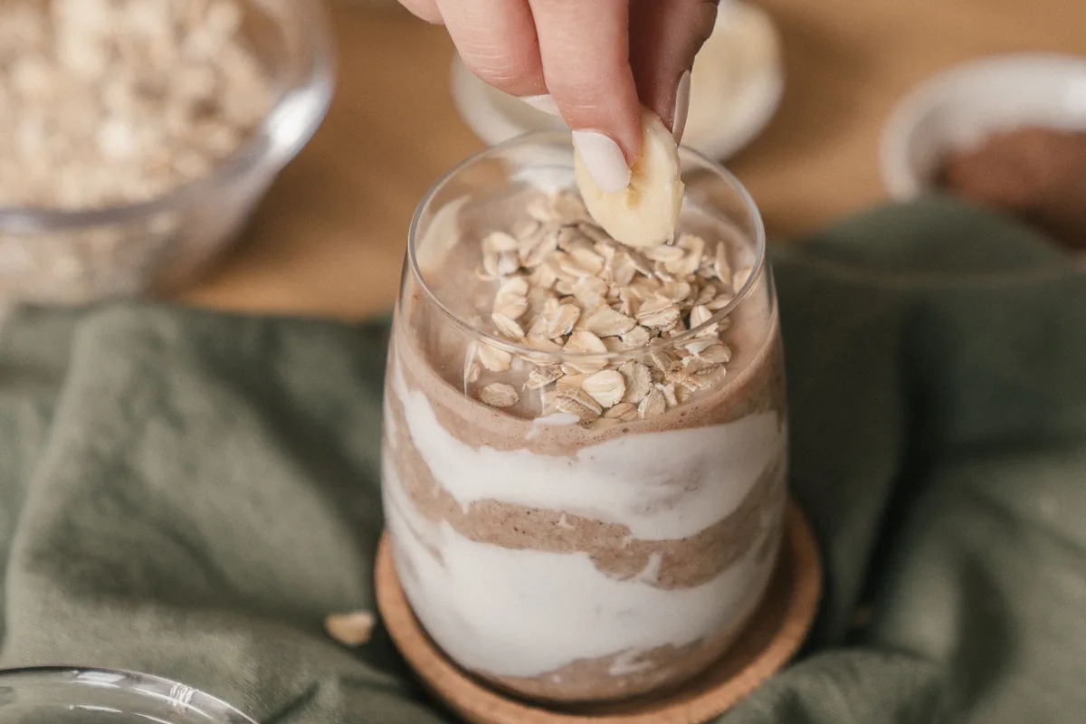 Banana being added to yoghurt and oats.