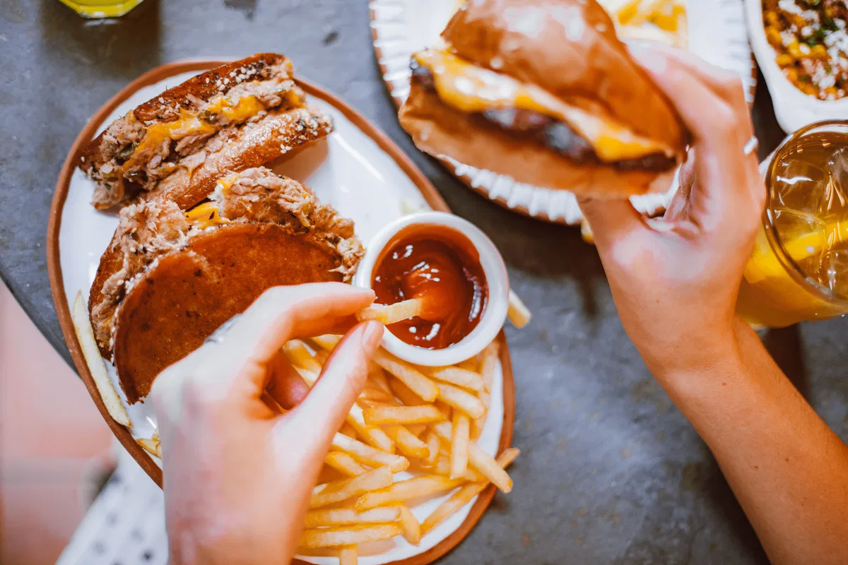 A burger, fries, pastries and other takeaway-style foods on a table.