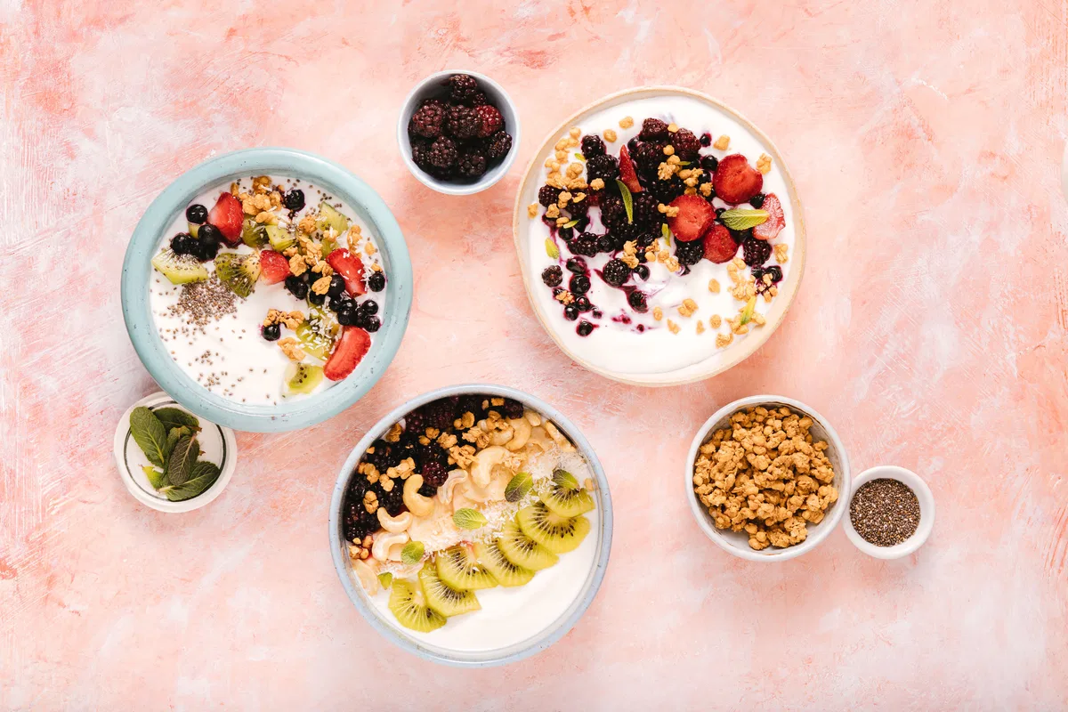 A small serving of mixed nuts with fruit, yoghurt and oats nearby.