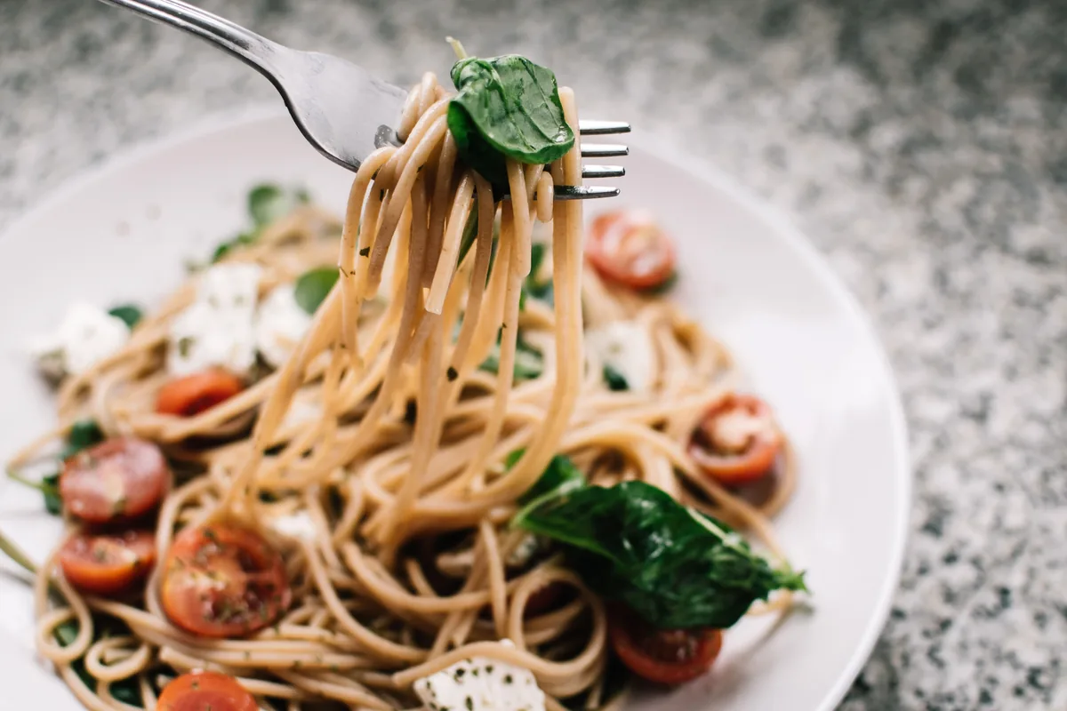 Pasta served with tomatoes, mushrooms and leafy greens.