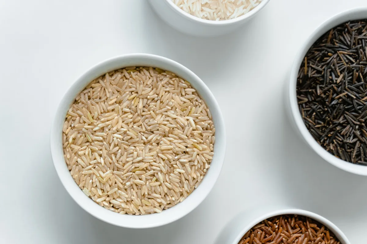 Brown, white and other rice varieties displayed in bowls.
