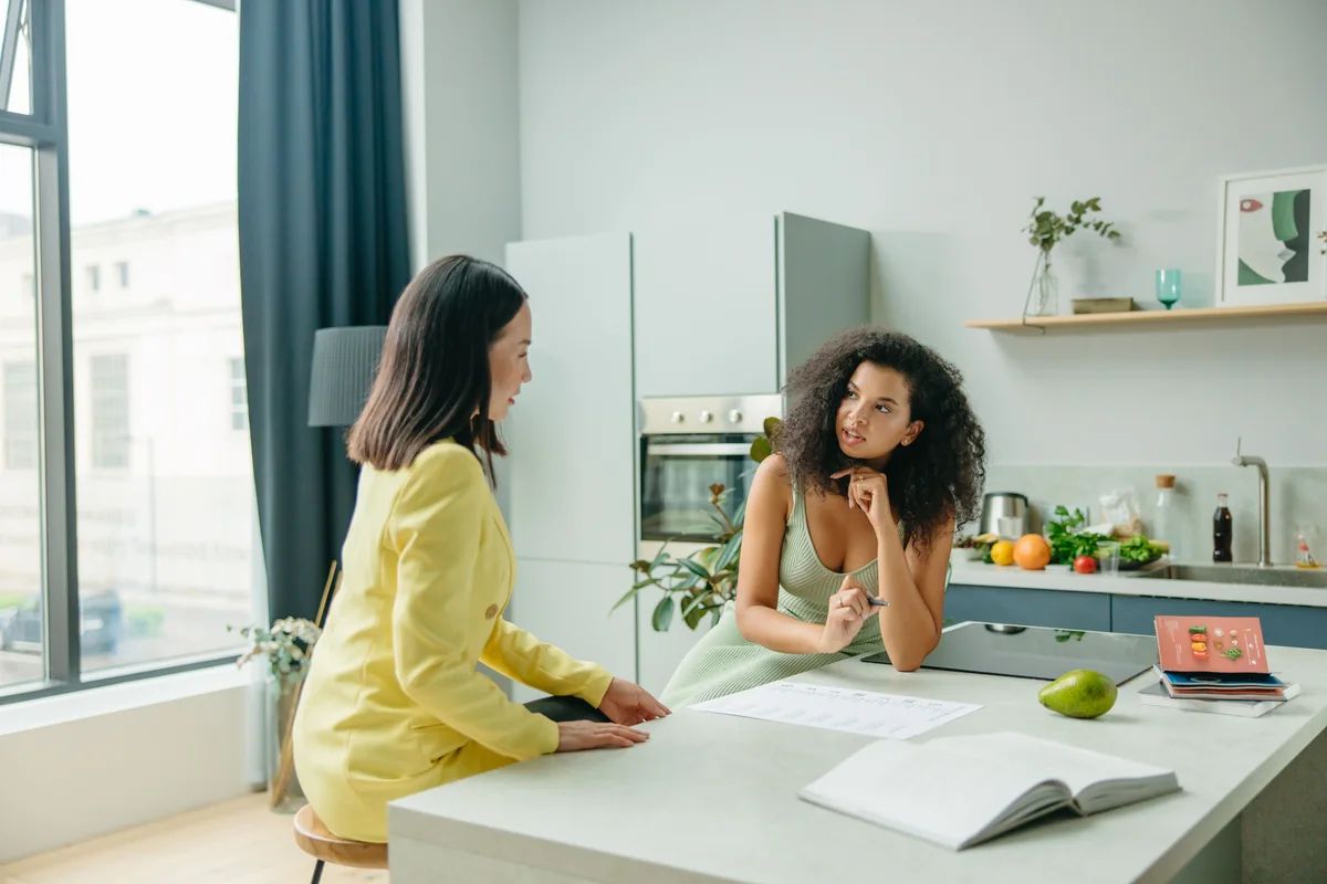 Two adults discussing meal planning in a kitchen.