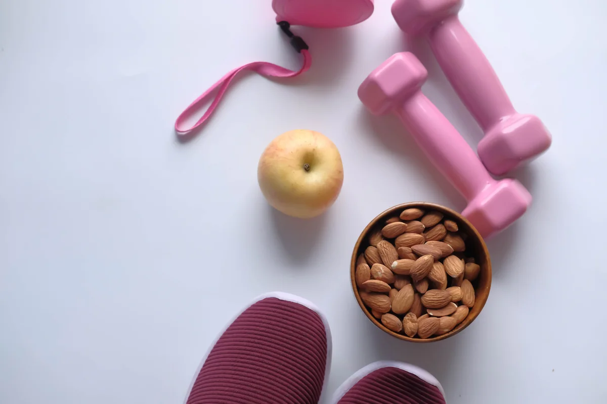 Exercise equipment, an apple and nuts arranged as everyday healthy-lifestyle essentials.