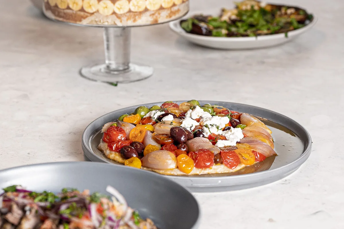 A table of Mediterranean-style dishes with vegetables, olives and other shared foods.