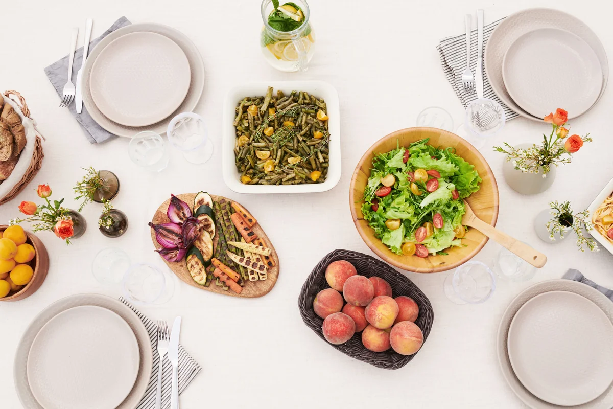 A dinner table set with several vegetable-rich dishes and salads.