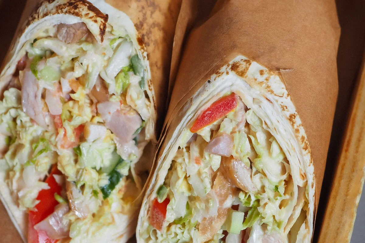 Two chicken wraps filled with crisp lettuce, cucumber and red pepper