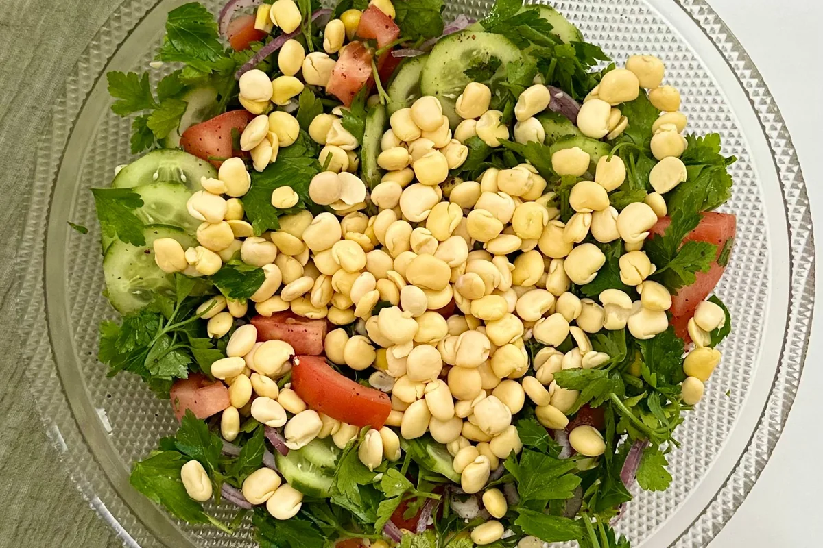 Fresh chickpea salad with cucumber, tomatoes and herbs in a glass bowl