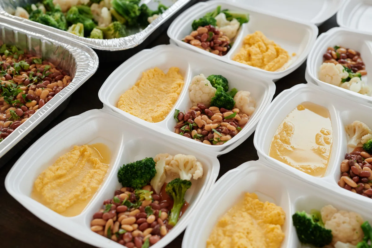 Meal-prep containers with beans, broccoli and other cooked components.